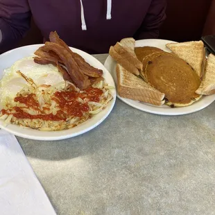 a man sitting at a table with two plates of breakfast food