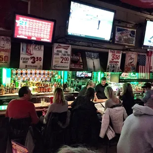 people sitting at the bar watching televisions