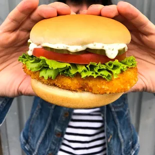 a woman holding a hamburger in front of her face