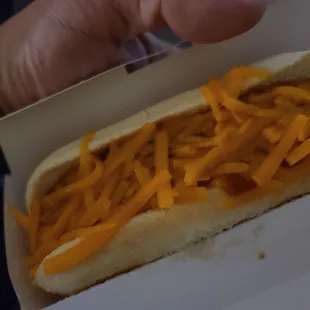 a person holding a hot dog with cheese on it
