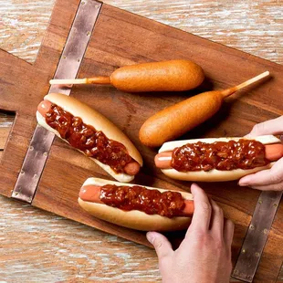 two hotdogs and two hot dogs on a cutting board