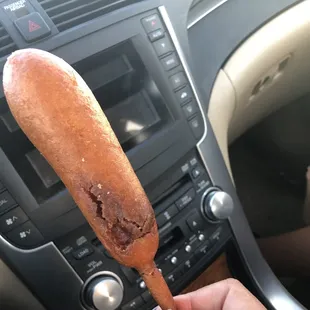 a person holding a hot dog in a car