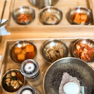 Mul naeng myeon (cold noodles in broth) and seolleongtang (ox bone soup with noodles) served on a tray with side dishes