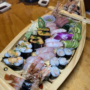 a wooden boat with sushi and shrimp