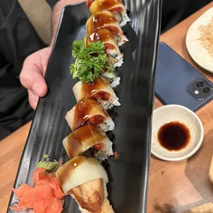 a person holding a plate of sushi