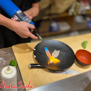 a person cooking food in a wok