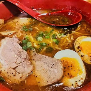 a bowl of ramen with an egg and a spoon