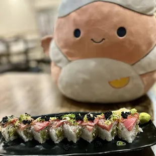 a plate of sushi with a stuffed animal in the background