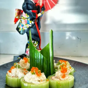 a plate of cucumbers with a doll in the background