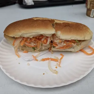 a half eaten sandwich on a paper plate