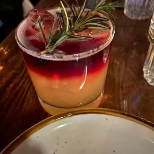 a cocktail with a sprig of rosemary