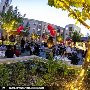 a crowd of people sitting at tables in a courtyard