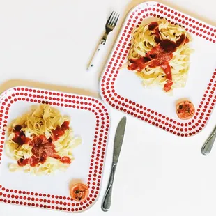 two plates of pasta with tomato sauce