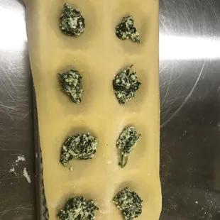 Stuffing the raviolis with spinach filling.