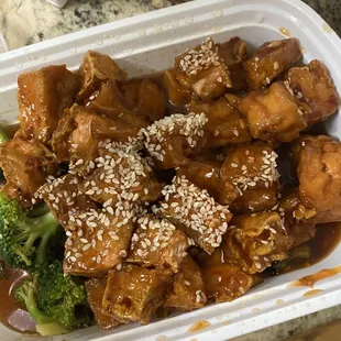 a takeout container of chicken and broccoli