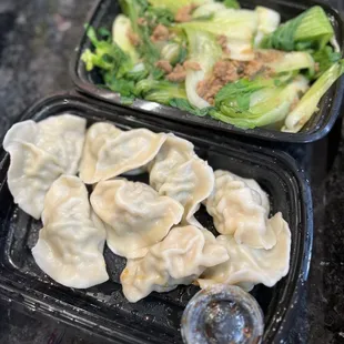 two trays of dumplings and a salad