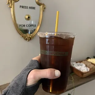 a hand holding a cup of iced coffee