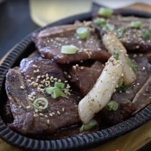 a plate of beef with onions and sesame seeds