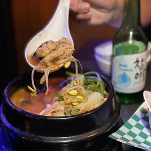 a person holding a spoon over a bowl of soup
