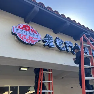 a man on a ladder working on a sign