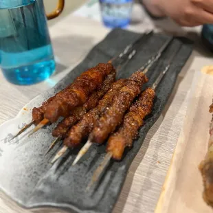 several skewered meats on a plate