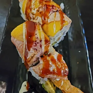 two pieces of sushi on a black plate
