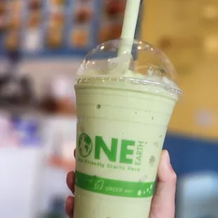 a hand holding a cup of green tea