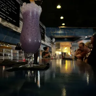 a purple drink sitting on a bar