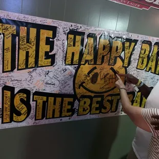 a man and a woman hanging a happy bar sign