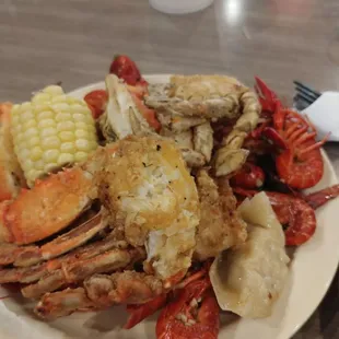 a plate of crab legs, corn, potatoes and corn on the cob