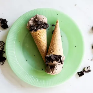 two ice cream cones on a green plate