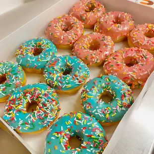 a box of glazed donuts with sprinkles