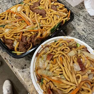 two plates of noodles with meat and vegetables
