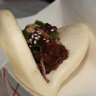 a close up of a bun with meat and vegetables