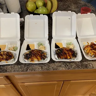 six takeout containers of food on a kitchen counter