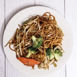 a plate of noodles with broccoli and carrots