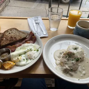 Biscuits and gravy, traditional breakfast with over easy eggs, bacon, and toast, OJ and coffee.