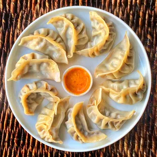 a plate of momos with a dipping sauce