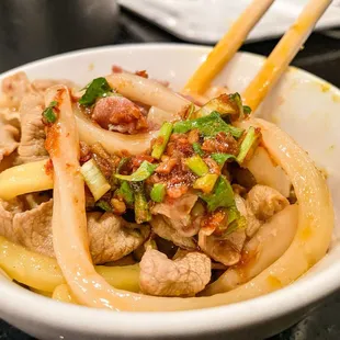 a bowl of food with chopsticks