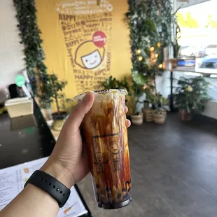 a hand holding a glass of iced coffee