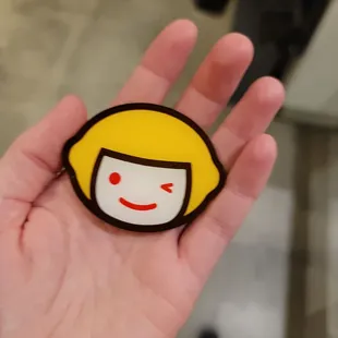  hand holding a smiley face pin