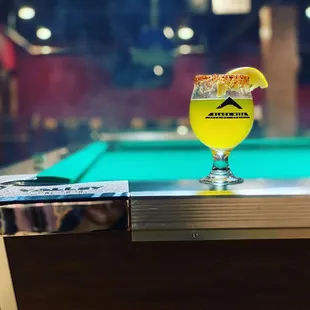 a glass of beer on a pool table