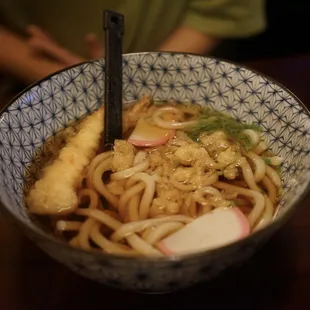 a bowl of ramen with a side of bread