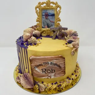 a yellow cake with a picture frame and seashells