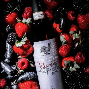 a bottle of wine surrounded by strawberries