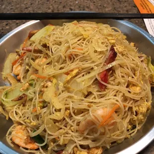 a plate of noodles with shrimp and vegetables