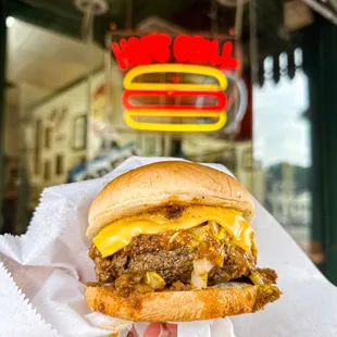 a hand holding a cheeseburger