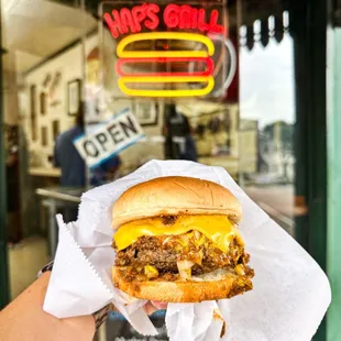 a hand holding a cheeseburger