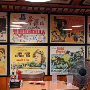 a table with a fan and posters on the wall