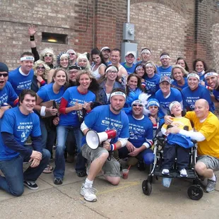 a large group of people in blue shirts posing for a picture